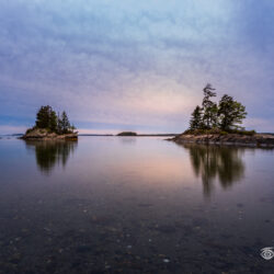Small rocky islands reflected in calm water at Lookout Point in Harpswell, Maine during spring evening light