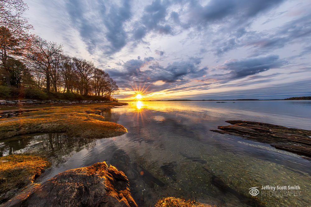 Sunrise reflections and dramatic clouds along the shoreline at Winslow Park in Freeport, Maine